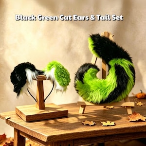 May include: A set featuring a headband with black, green, and white faux fur cat ears and a matching long, curved, black and green faux fur tail. The text Black Green Cat Ears & Tail Set is displayed above the items on the wooden stands.