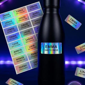 May include: A black water bottle with a holographic label displaying the name "EMMA" and a phone number. Scattered around are several holographic name labels with names such as "SARAH" and "JAMES".