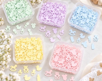 May include: Five square clear plastic containers filled with small, flat, baby-themed confetti shapes in pastel mint green, lavender, light blue, pale yellow, and soft pink. Each container holds assorted shapes including teddy bears, ducks, baby bottles, onesies, pacifiers, and rocking horses.