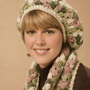 May include: A crocheted beret and matching scarf set featuring a granny square pattern in shades of sage green, dusty rose, and cream. The beret has a rounded shape with a cream-coloured border, and the scarf displays a repeating textured stitch.