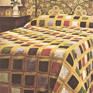 May include: A crochet bedspread featuring a grid of mustard yellow yarn borders surrounding individual square motifs in various colors including dark brown, red, white, green, and light purple, creating a textured, multi-colored geometric pattern.