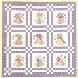 May include: A square quilt featuring a grid of nine white blocks, each displaying an applique of a figure wearing a wide-brimmed hat and a multi-colored patchwork skirt. The blocks are separated by purple floral sashing and corner squares.