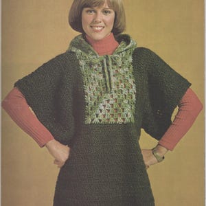 May include: A dark green crocheted hooded poncho featuring a square-shaped panel on the chest with a variegated light green and white granny square pattern, a drawstring hood, and short sleeves, worn over a coral-colored long-sleeve turtleneck.