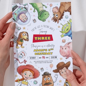 May include: A rectangular birthday invitation card featuring colorful cartoon illustrations of various toy characters. The text reads: You've got a friend who's turning THREE. Please join us in celebrating ADAM'S 3RD BIRTHDAY. SATURDAY NOV 14 2026 2:00 PM.