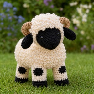 May include: A crochet sheep stuffed animal featuring a cream-colored textured body, a solid black face, black ears, and two curved tan horns. The legs are cream-colored with black circular spots and black hooves at the base of each limb.