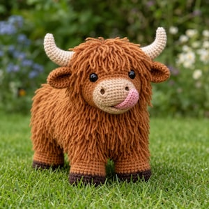May include: A crocheted Highland cow stuffed animal with long, shaggy, rust-coloured yarn fur, a light tan muzzle, and cream-coloured horns. The toy features black button eyes and a small, pink, tongue-shaped accent protruding from its mouth.