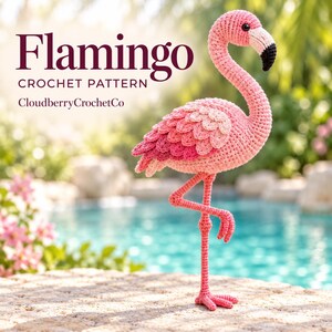 Puede incluir: Un juguete de flamenco tejido a ganchillo con tonos de hilo rosa, un cuello largo y curvado y un pico con punta negra. El texto Flamingo CROCHET PATTERN CloudberryCrochetCo es visible. El flamenco se apoya en una pata con alas texturizadas.
