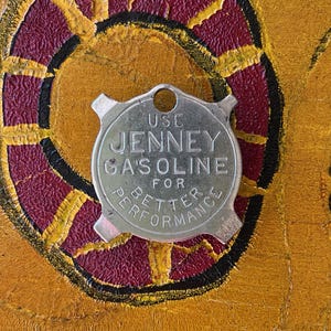 May include: A silver metal key chain with a round tag that says "Use Jenney Gasoline for Better Performance".