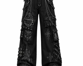 May include: Black wide-leg cargo pants featuring silver-tone chains, metal D-rings, and multiple pockets. The fabric is decorated with dark grey graphic prints of skulls, bats, and crosses, along with side straps, buckles, and lace-up details.