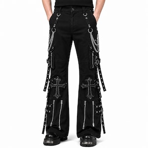 Puede incluir: Pantalones cargo negros con cadenas de metal plateado, múltiples bolsillos laterales con cremalleras, correas ajustables con hebillas y grandes parches de cruces bordados en la parte delantera de cada pierna. Corte ancho con herrajes metálicos.