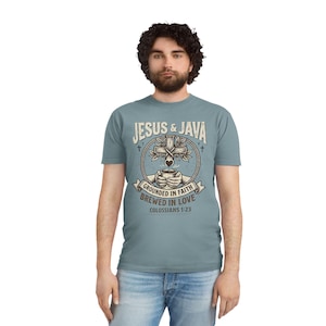 May include: A light blue t-shirt with the text "JESUS & JAVA" above a graphic of a cross, coffee cup, and the words "GROUNDED IN FAITH BREWED IN LOVE COLOSSIANS 1:23". The shirt is worn by a person.