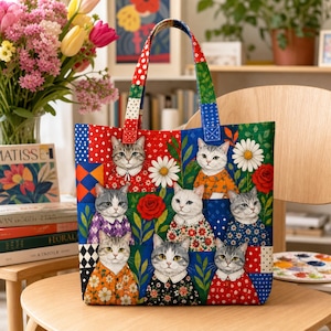 May include: A fabric tote bag featuring a patchwork design of cats wearing patterned shirts, interspersed with red roses and white daisies. The bag has two matching fabric handles and a colourful, multi-patterned background of polka dots, diamonds, and floral prints.