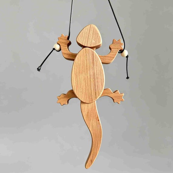 A hand-carved wooden gecko that actually climbs and ripples with kinetic motion — mechanical sculpture meets stress toy in the most satisfying way.