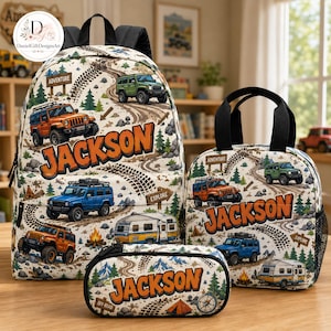 May include: A backpack, lunch bag, and pencil case set featuring an off-road adventure print with orange, blue, and green SUVs, a camper, trees, and tire tracks. Each item is personalized with the name JACKSON in large orange letters.
