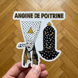 May include: A die-cut sticker featuring the text ANGINE DE POITRINE in black letters with a gold outline. The design displays two figures with polka-dot patterns, one white with black dots and one black with white dots, both featuring gold accents.