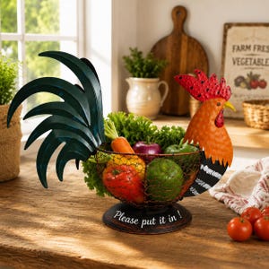 Puede incluir: Una cesta de metal para frutas y verduras con forma de gallo y cuerpo de malla de alambre. El gallo presenta una cola verde oscuro, cabeza naranja con cresta roja y una base negra con el texto blanco "Please put it in !" impreso.