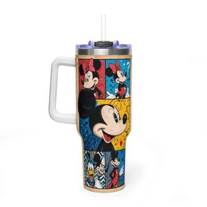 May include: A large tumbler with a white handle and a straw. The tumbler has a colourful pop art design featuring Mickey and Minnie Mouse, plus other Disney characters. The background is a mix of blue, red, and yellow.