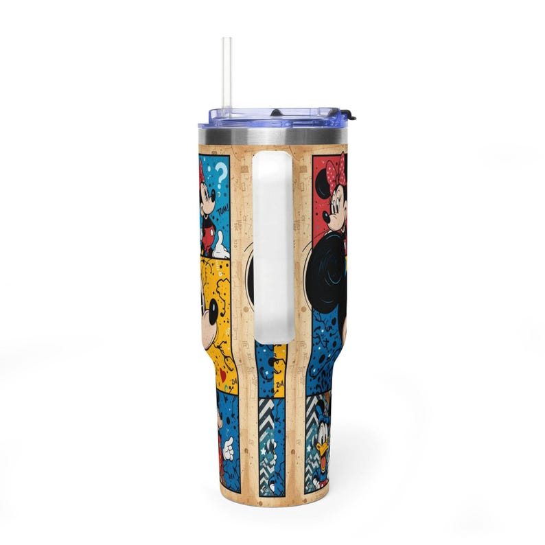 May include: A stainless steel tumbler with a comic strip design featuring Mickey and Minnie Mouse, and Donald Duck. The tumbler has a white handle, a clear straw, and a blue lid. The background has a wood-like texture.