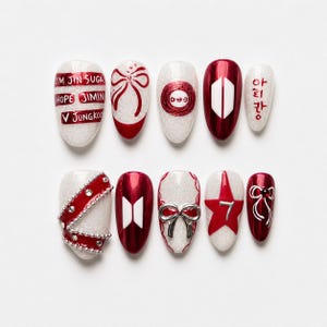 Pode incluir: Um conjunto de dez unhas postiças com base de glitter branco e detalhes em vermelho. Os designs incluem laços vermelhos, o logotipo do BTS, o número 7, tachas prateadas e texto com nomes como Jin, Suga, Hope, Jimin, V e Jungkook em vermelho.
