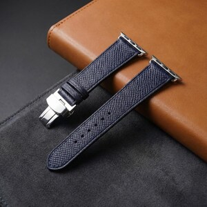 Pode incluir: Uma pulseira de relógio em couro texturizado azul-marinho com um fecho borboleta de metal prateado e adaptadores de metal prateado para fixação. A pulseira tem um acabamento de superfície granulada e inclui orifícios de ajuste.