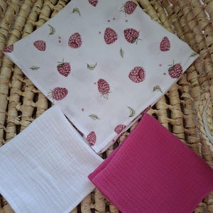 Könnte beinhalten: Ein Set aus drei quadratischen Musselintüchern. Ein Tuch hat einen weißen Hintergrund mit einem wiederkehrenden Muster aus rosa Himbeeren und kleinen grünen Blättern. Das zweite Tuch ist einfarbig weiß und das dritte ist einfarbig dunkelrosa.