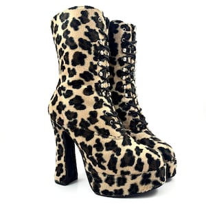 May include: A pair of black and brown leopard print platform boots with silver studs on the laces. The boots have a chunky heel and a platform sole.