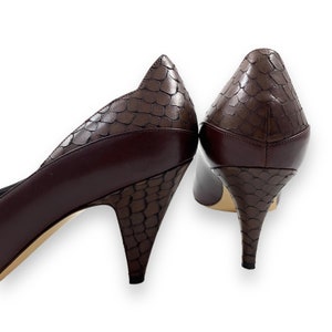 Può includere: Un paio di décolleté in pelle marrone con tacco alto e motivo a stampa di pelle di serpente. I tacchi sono di tipo stiletto.