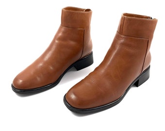 May include: A pair of brown leather ankle boots with a low heel and a zipper on the side.