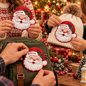 May include: Three embroidered Santa Claus patches featuring the name Oliver in red script, a white beard, a red hat with green holly leaves, and a white pom-pom. The patches are shown being applied to a cream knit beanie and a dark green backpack.