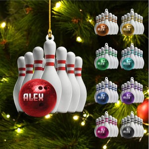 May include: A hanging Christmas tree ornament featuring a set of white bowling pins with red stripes and a red bowling ball with the name ALEX printed on it. The ornament is displayed in multiple color variations including orange, gold, green, teal, blue, purple, pink, and grey.