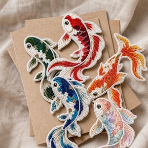 May include: Five embroidered koi fish patches featuring intricate thread work in vibrant colors including red, white, green, blue, orange, and pastel rainbow scales. Each fish has a distinct pattern, detailed fins, and a small eye, arranged together.