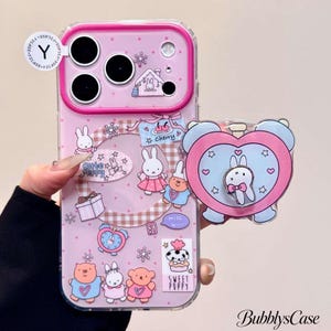 May include: A clear phone case with a pink polka dot pattern featuring various cartoon characters, including Miffy, and a heart-shaped alarm clock phone grip. The case includes text such as "Cute Miffy," "cherry," "miss u," and "Sweet Puppy."
