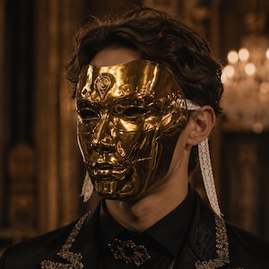 May include: A shiny gold-colored face mask with intricate embossed detailing, featuring white lace ribbons attached to the sides. The mask covers the upper face and nose, secured by the lace ties, and is worn over a dark collared shirt with gold trim.