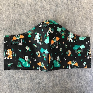 May include: Black face mask with a repeating pattern of green, orange, and white illustrations of creatures and plants on a black background.