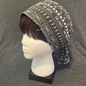 May include: Black and white patterned surgical cap with the text "EW. DAVID" repeated on the fabric. The cap is worn on a white mannequin head.