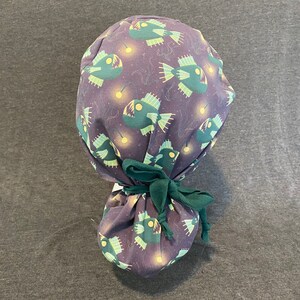 May include: A purple scrub hat with a green tie. The hat has a repeating pattern of anglerfish with glowing lures.