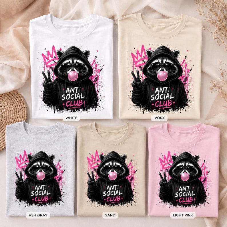 May include: A collection of t-shirts in various colors, including white, ivory, ash gray, sand, and light pink. Each shirt features a graphic of a raccoon wearing a hoodie and sunglasses, blowing a bubblegum bubble, with the text "ANT SOCIAL CLUB".