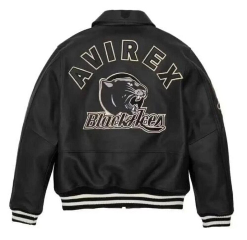May include: A black varsity jacket featuring the text AVIREX in an arched font above a graphic of a panther head and the text Black Aces. The jacket has a collar, long sleeves, and black and white striped ribbed cuffs and hem.