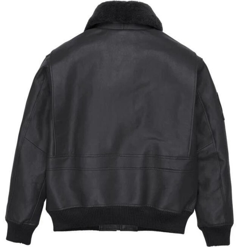 May include: A black leather bomber jacket featuring a dark gray faux fur collar, long sleeves with ribbed cuffs, and a ribbed hem. The back of the jacket displays a smooth leather finish with horizontal seam detailing across the mid-section.