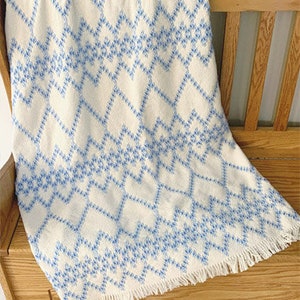 May include: White throw blanket with a blue diamond pattern and fringe trim.