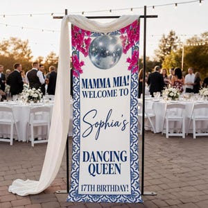 Puede incluir: Una pancarta vertical con el texto "MAMMA MIA! WELCOME TO Sophia's DANCING QUEEN 17TH BIRTHDAY!" presenta una bola de discoteca y detalles florales rosas. La pancarta está enmarcada por un soporte de metal negro y tela blanca. Mesas e invitados al fondo.