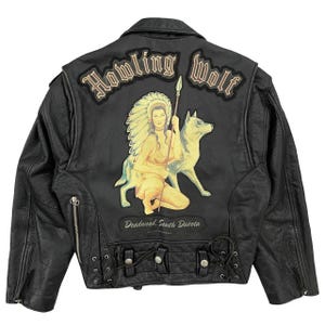 May include: Black leather jacket with a "Howling Wolf" design on the back. The design features a Native American woman, a wolf, and the text "Deadwood, South Dakota". The jacket has a classic biker style with zippers and a button closure.