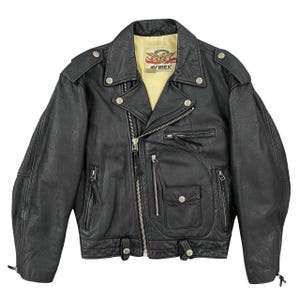 May include: Black leather biker jacket with a notched collar, multiple zipped pockets, and snap fastenings. The jacket has a yellow lining and the "AVIREX" logo. The jacket has a classic biker style.