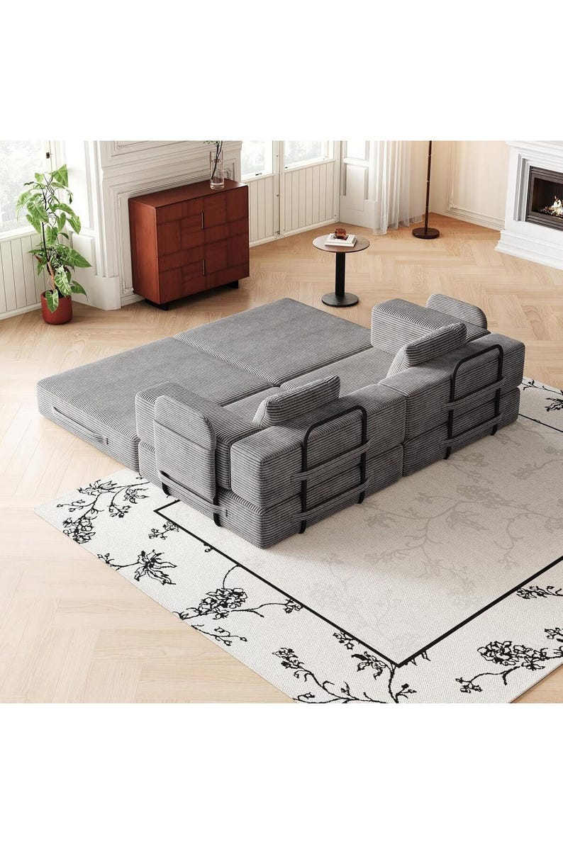 May include: A modular gray corduroy sofa bed featuring a textured fabric finish, black metal frame supports on the back and sides, and multiple rectangular cushions. The piece is configured in a partially extended position with a flat sleeping surface.