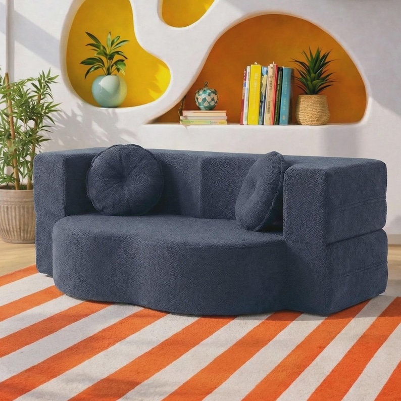 May include: A dark blue, curved sofa with a textured fabric finish, featuring two matching round throw pillows. The sofa has a low-profile, modular design with a rounded seat and straight backrest, providing a solid, uniform appearance.