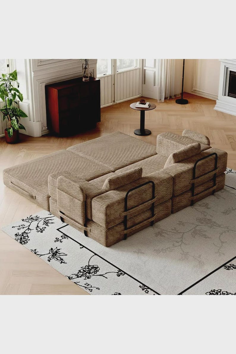 May include: A modular sofa bed upholstered in tan corduroy fabric, featuring a low-profile design with black metal frame supports on the sides. The sofa is configured in a partially extended position, showcasing its rectangular cushions and structure.