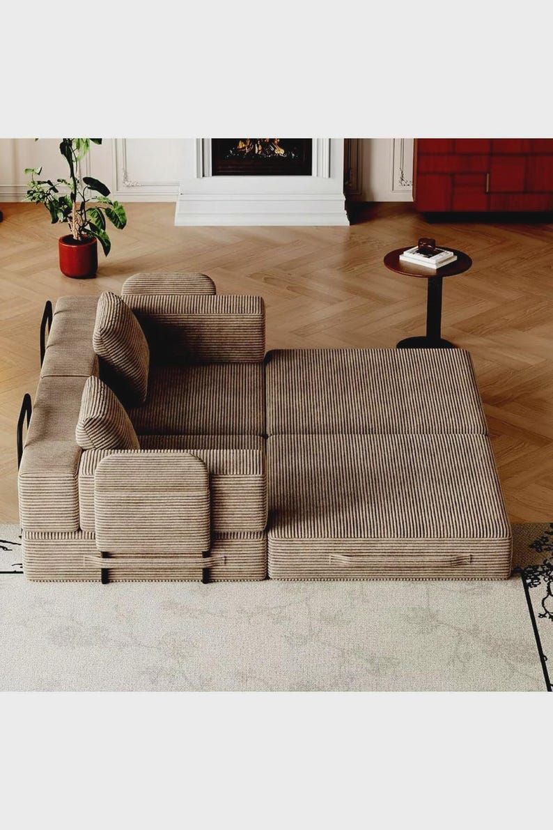 May include: A modular sofa bed upholstered in a light brown corduroy fabric. The piece features a low-profile design with integrated armrests, two back cushions, and a flat, extended base section that can be configured for seating or sleeping.