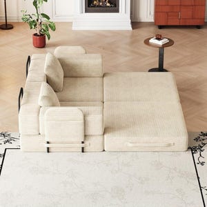 May include: A beige corduroy modular sofa bed featuring a textured fabric finish, black metal frame accents, and two matching square throw pillows. The piece is configured in a partially extended position with a flat, rectangular sleeping surface.
