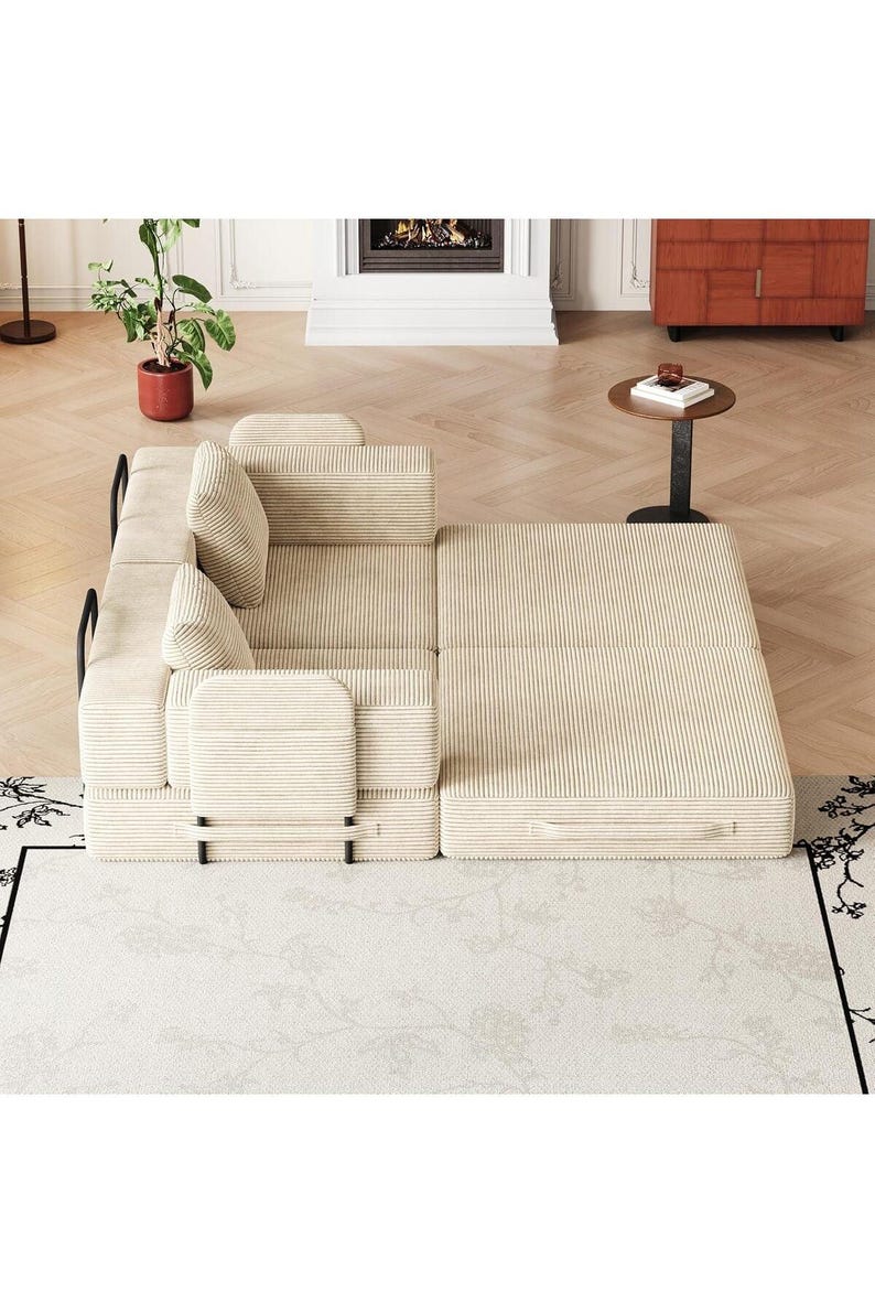 May include: A beige corduroy modular sofa bed featuring a textured fabric finish, black metal frame accents, and two matching square throw pillows. The piece is configured in a partially extended position with a flat, rectangular sleeping surface.