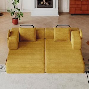 May include: A mustard yellow corduroy sofa bed featuring a low-profile design with two square cushions, two rectangular armrests, and two black metal handles visible at the back. The upholstery has a distinct horizontal ribbed texture.